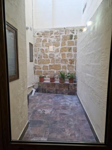 un pasillo con una pared de piedra y macetas en Sir Patrick's rooms & hostel, en Għajn il-Kbira