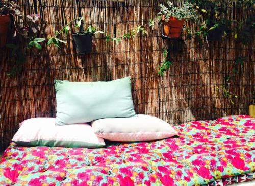 - un lit avec deux oreillers à côté d'un mur orné de plantes dans l'établissement Maison au Vallon des Auffes Marseille, à Marseille