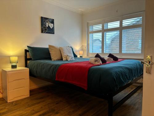 a bedroom with a bed with a red and blue blanket at House few mins from beach with hot tub & sauna in Shoreham-by-Sea