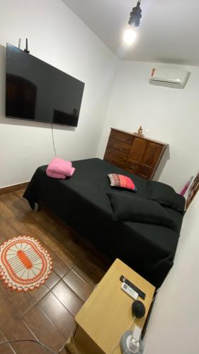 een slaapkamer met een bed en een flatscreen-tv bij Quarto aconchegante II in Cruzeiro