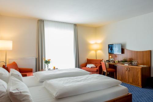 ein Hotelzimmer mit 2 Betten und einem Schreibtisch in der Unterkunft Komforthotel Butjadinger Tor in Nordenham