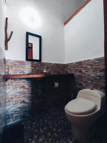 a bathroom with a toilet and a brick wall at Casa Hermosa Vista Barichara in Barichara
