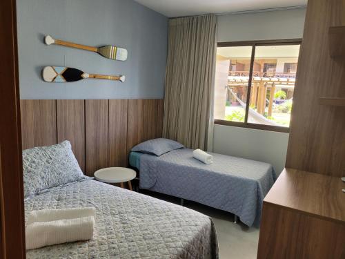 a hotel room with two beds and a window at Village Beira Mar Itacimirim Boulevard Bahia in Itacimirim