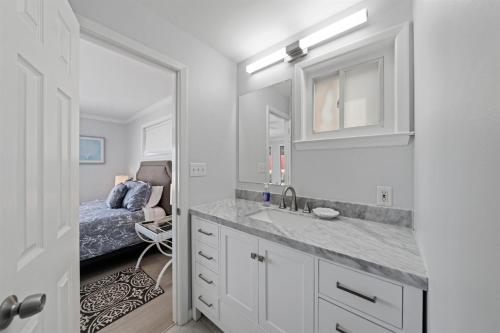 ein weißes Badezimmer mit Waschbecken und Bett in der Unterkunft Ocean Oasis Kure Beach Ocean front, Pool coming soon! in Kure Beach