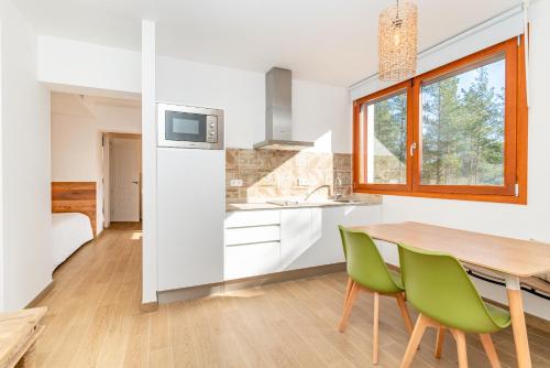 cocina con mesa de madera y sillas verdes en Ginkgo - Familienfreundliches Appartment in Katalanischer Masia, en Sant Iscle de Vallalta