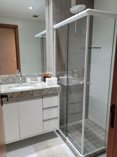 a bathroom with a glass shower and a sink at Village Beira Mar Itacimirim Boulevard Bahia in Itacimirim