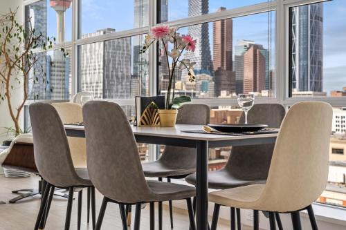 uma sala de jantar com mesa e cadeiras e uma grande janela em Luxury Corner Unit w Panoramic Tower & Downtown Skyline Views! FREE Banff Pass, Wine, Gym & Parking! em Calgary