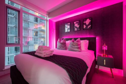 een slaapkamer met een bed met roze verlichting bij Luxury Corner Unit w Panoramic Tower & Downtown Skyline Views! FREE Banff Pass, Wine, Gym & Parking! in Calgary