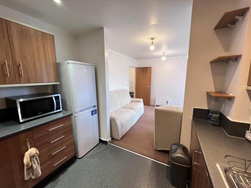 een kleine keuken met een koelkast en een bank bij Luxury 2 beds Apartment with 2 bathrooms, living dining & Parking - East London in Barkingside