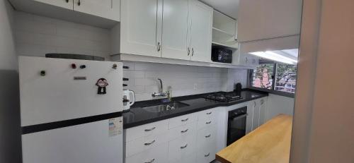 uma cozinha com armários brancos e um frigorífico branco em apto 1 dorm sobre Ellauri em Montevidéu