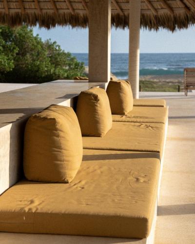 a row of pillows sitting on a bench at a beach at Mazul Puerto Escondido in Tlachicón