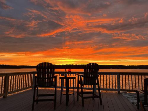 two chairs and a table on a deck with a sunset at Wake N Lake in Littleton
