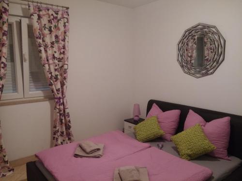 una camera da letto con letto e lenzuola e cuscini rosa di Hostel **Casa del Sole** a Klenovica