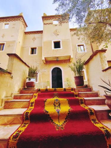 a building with a red and yellow carpet in front of it at Riad Kasbah des Roches in Akhendachou nʼAït Ouffi