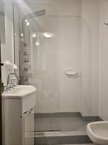 a white bathroom with a shower and a sink at 3 Ambientes frente al Golf - Playa Grande in Mar del Plata