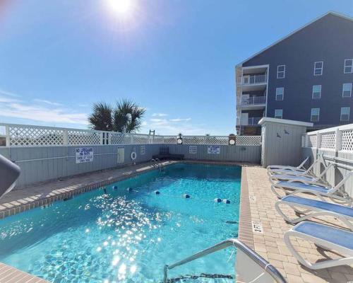 a large swimming pool with chairs and a building at Beachy Condo right on Oceanfront in Myrtle Beach