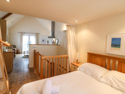 a bedroom with a bed and a kitchen in the background at The Loft Cottage in Totnes