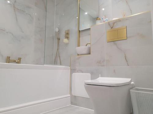 La salle de bains blanche est pourvue d'une douche et de toilettes. dans l'établissement Beautiful New built 2 bedroom apartment, à Purley