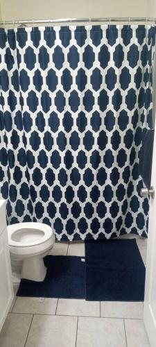 a bathroom with a toilet and a blue and white shower curtain at the rest spot in Schenectady