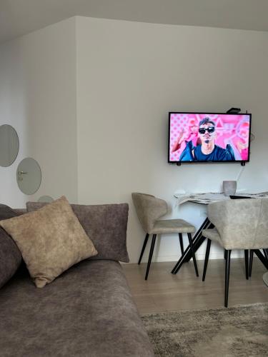 sala de estar con sofá y TV en la pared en New Bazar Retreat Apartment, en Tirana