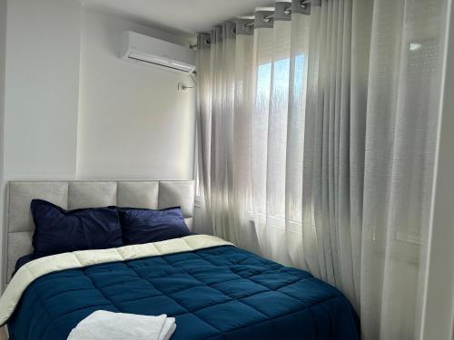 Un dormitorio con una cama con almohadas azules y una ventana en New Bazar Retreat Apartment, en Tirana
