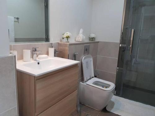a bathroom with a toilet and a sink and a shower at Cosy 1 bedroom in Damac Hills in Dubai