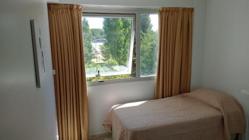 ein Schlafzimmer mit einem Bett und einem großen Fenster in der Unterkunft Departamento en la Costa del Rio Limay (Neuquen Capital) in Neuquén