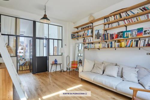 uma sala de estar com um sofá branco e estantes em 60 m nest near the Atelier des Lumières em Paris