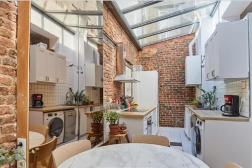 uma cozinha industrial com electrodomésticos brancos e uma parede de tijolos em 60 m nest near the Atelier des Lumières em Paris