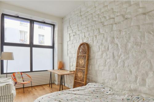 um quarto com uma parede de pedra, uma cama e uma mesa em 60 m nest near the Atelier des Lumières em Paris