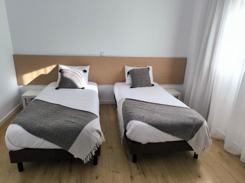 2 łóżka w pokoju z białymi ścianami i drewnianą podłogą w obiekcie Suitel Pombal w mieście Pombal