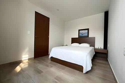 een slaapkamer met een wit bed en een houten vloer bij Apartaestudio CDMX, zona norte in Mexico-Stad