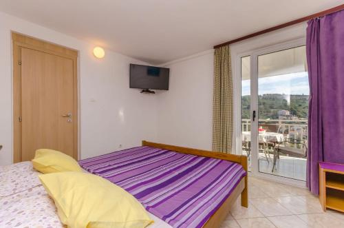 a bedroom with a bed with purple sheets and a window at Apartments Vlado in Trogir