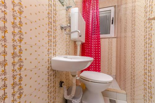 a bathroom with a toilet and a red shower curtain at Apartments Vlado in Trogir