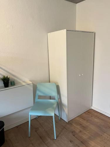 ein blauer Stuhl neben einem weißen Schrank in der Unterkunft Mikro Apartment Großenhain in Großenhain