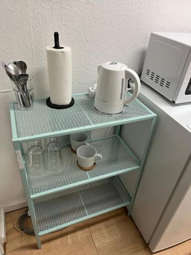 Mikro Apartment Großenhain في وغروسنهاين: رف مع آلة صنع القهوة وأكواب عليه