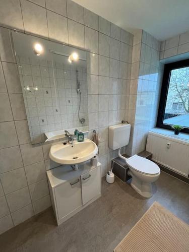 ein Badezimmer mit einem Waschbecken, einem WC und einem Spiegel in der Unterkunft Mikro Apartment Großenhain in Großenhain