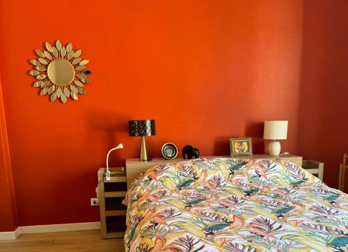 a bedroom with an orange wall with a bed and a mirror at La Favolosa casa di Amelie in Bologna