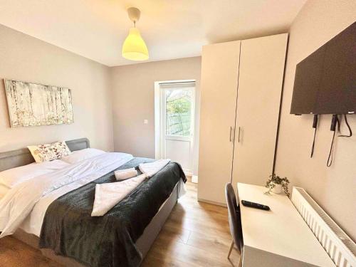 a bedroom with a bed and a desk and a television at The Winstre Borehamwood in Borehamwood