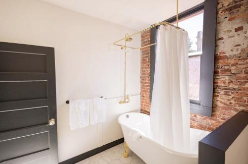 a bathroom with a white tub and a brick wall at Speakeasy King Suite (Rm1) in Nevada City