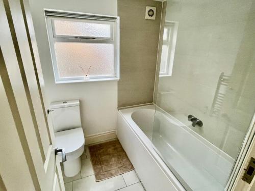 a bathroom with a tub and a toilet and a window at Central Morden, Westfield, close to Tube station in London