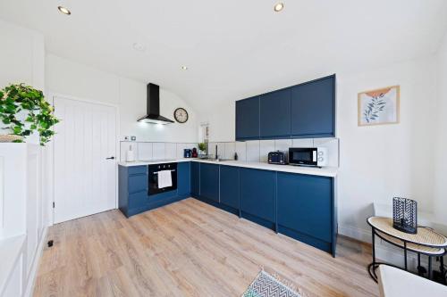 a kitchen with blue and white cabinets and a table at The Buccleuch Luxury Apartments in Kettering