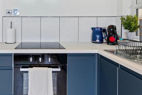 a kitchen with blue cabinets and a sink at The Buccleuch Luxury Apartments in Kettering