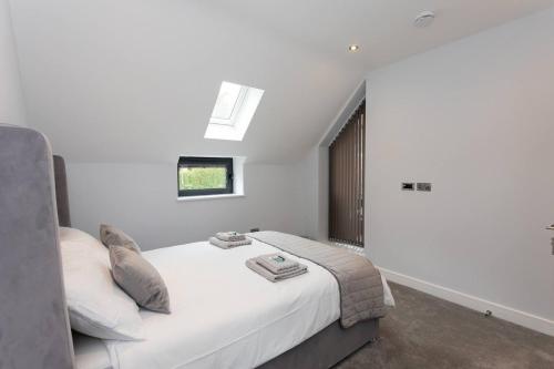 a bedroom with a white bed with a window at D & D Luxury Apartments in Stanmore