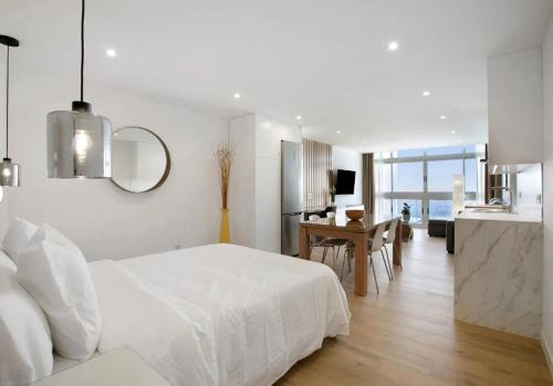 a white bedroom with a white bed and a kitchen at Luxury Loft Mar y Sol 1 in Tacoronte