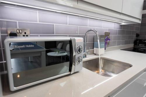 a kitchen counter with a microwave and a sink at D & D Luxury Apartments in Stanmore