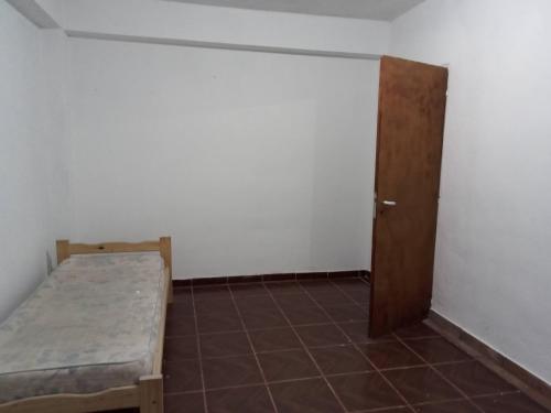 een kleine kamer met een bed en een deur bij Las Margaritas in Neuquén