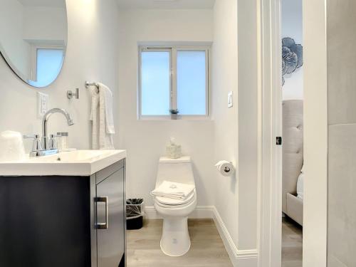 a white bathroom with a toilet and a sink at Luxe Home - Heated Pool I 5 min to Beach I BBQ Grill in Fort Lauderdale