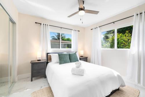 a bedroom with a white bed and two windows at Modern Bungalow near Wilton Drive I Pool Table in Fort Lauderdale