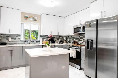 a kitchen with white cabinets and a stainless steel refrigerator at Modern Bungalow near Wilton Drive I Pool Table in Fort Lauderdale